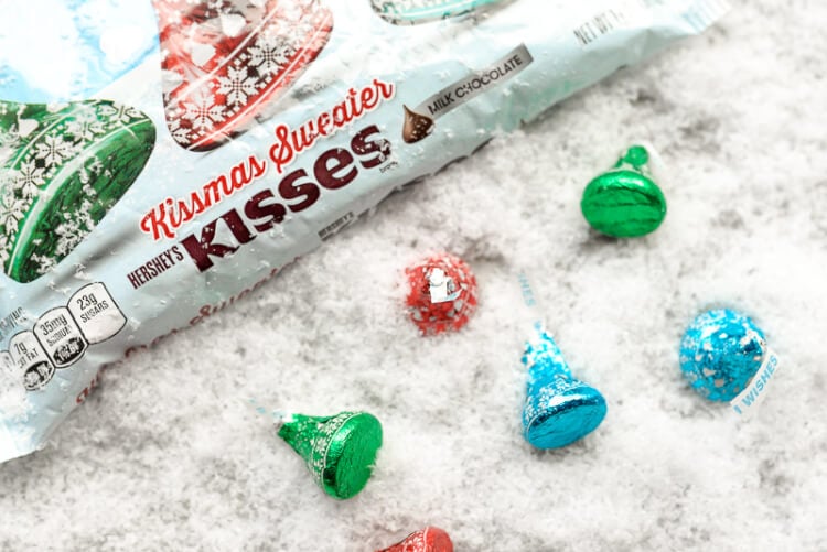 A package of Hershey\'s Kissmas Sweater Kisses next to more Hershey\'s kisses, all sitting on a table
