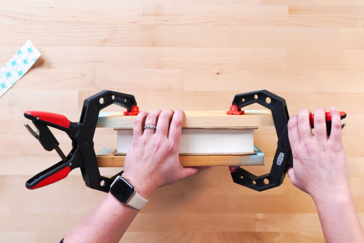 Hands attaching clamps to a book that is being readied to spray paint the edges