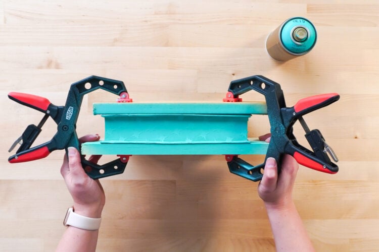 Hands attaching clamps to a book that is being readied to spray paint the edges
