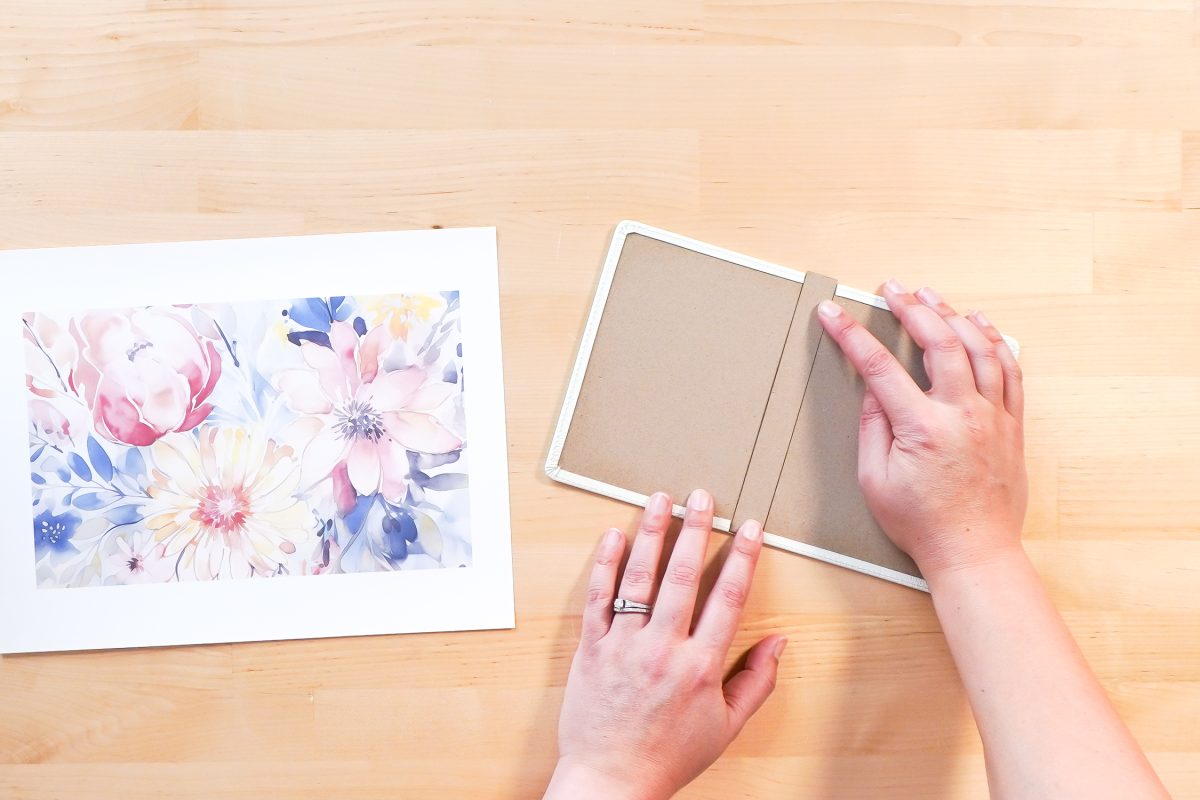 Hands adding the extra cardboard piece between the covers
